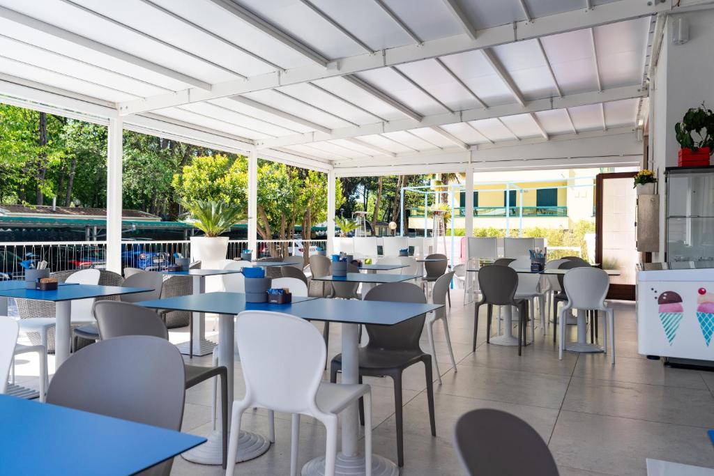 un restaurant avec des tables, des chaises et des fenêtres dans l'établissement Hotel Regina, à Caorle