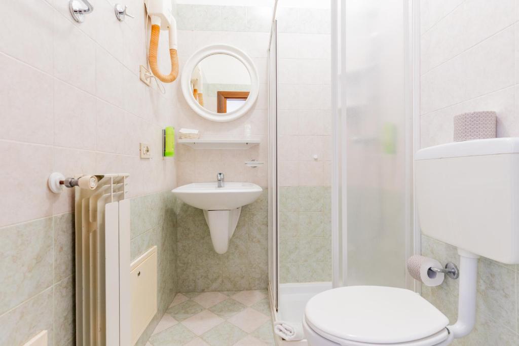 une salle de bain avec un lavabo, des toilettes et un miroir dans l'établissement Hotel Regina, à Caorle 46 autres photos
