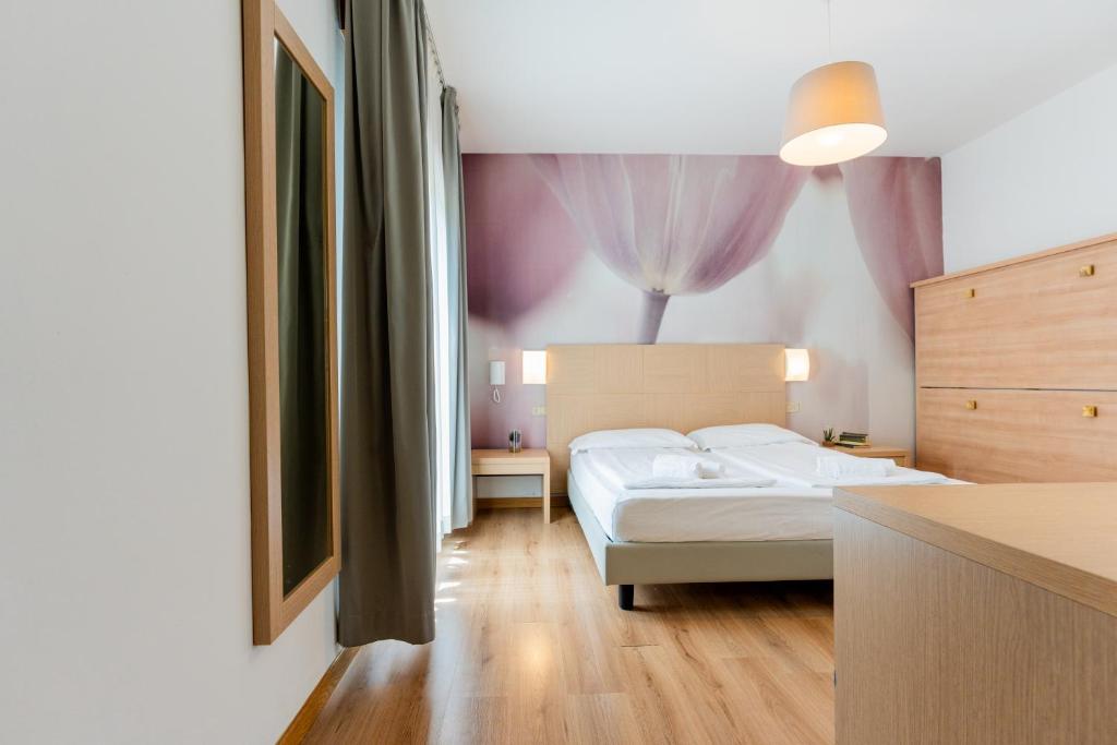 - une chambre avec un lit blanc et un mur violet dans l'établissement Hotel Regina, à Caorle
