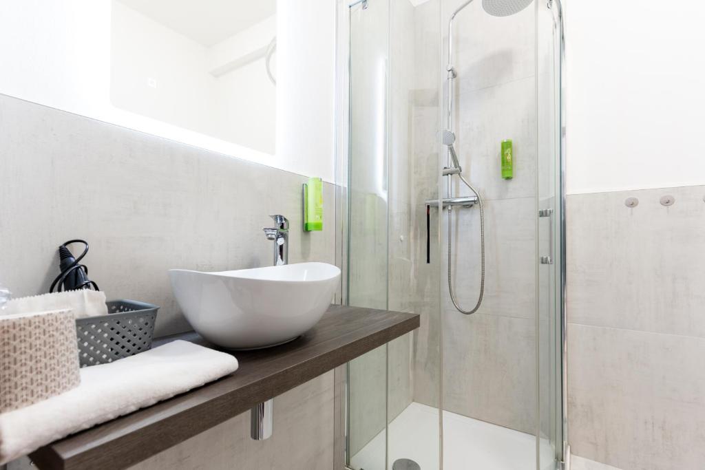 une salle de bain avec un lavabo et une douche dans l'établissement Hotel Regina, à Caorle