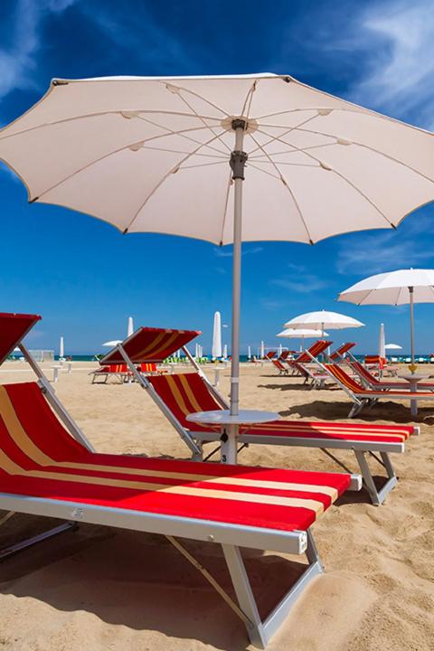 - un groupe de chaises et un parasol sur une plage dans l'établissement Hotel Anversa Rimini, à Rimini