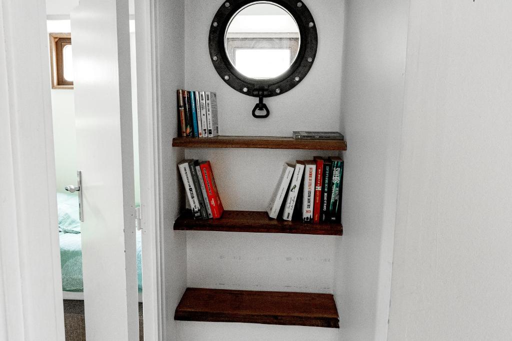 un couloir avec un miroir et des livres dans l'établissement Nuit insolite à bord d'une péniche, 6 personnes, à Bergues