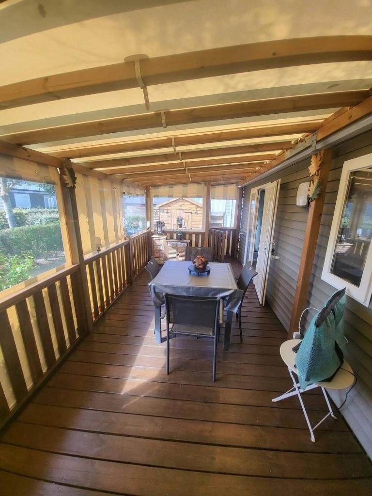 une terrasse couverte d'une maison avec une table et des chaises dans l'établissement Mobil-Home Montmartin-sur-mer, à Hauteville-sur-Mer
