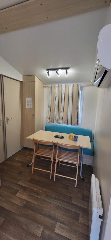Cette petite chambre comprend une table et un canapé bleu. dans l'établissement Mobil home - Camping La Palmeraie, à Torreilles