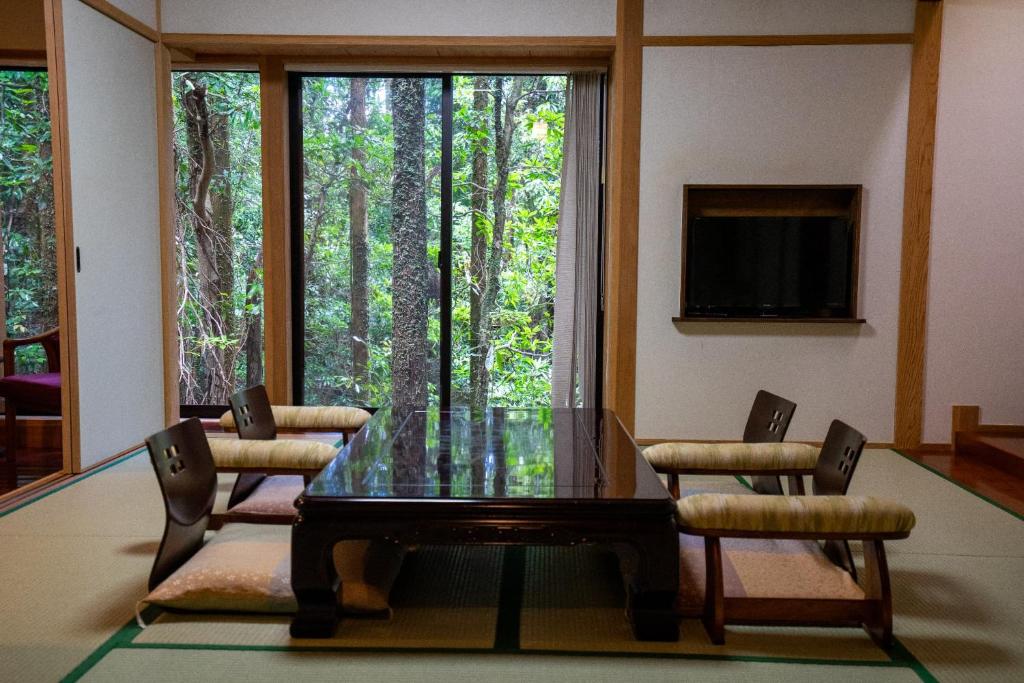 une salle à manger avec une table et des chaises en verre ainsi qu'une fenêtre dans l'établissement Jomon no Yado Manten, à Yakushima