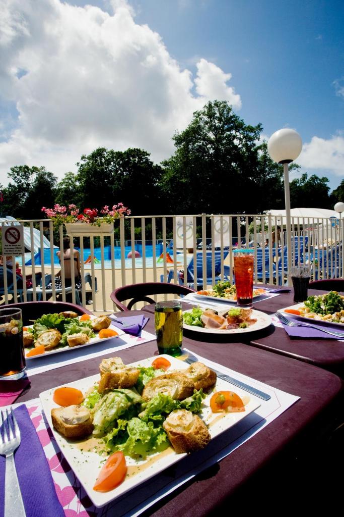 - une table avec des assiettes de nourriture et une piscine dans l'établissement Camping Officiel Siblu Les Pierres Couchees, à Saint-Brévin-les-Pins