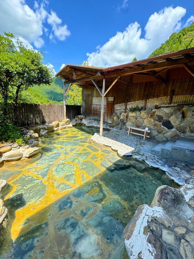 un bassin d'eau à côté d'un bâtiment avec un banc dans l'établissement Yunominesou, à Hongu