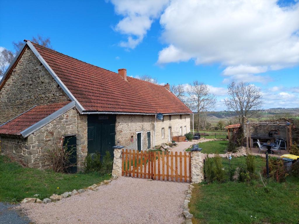 une vieille maison en pierre avec une clôture dans une cour dans l'établissement Gite Charassat, à Saint-Marcel-en-Marcillat