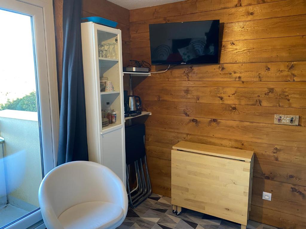Cette chambre comprend une chaise blanche et une télévision murale. dans l'établissement Les Balcons d'Edelweiss, à Chamrousse