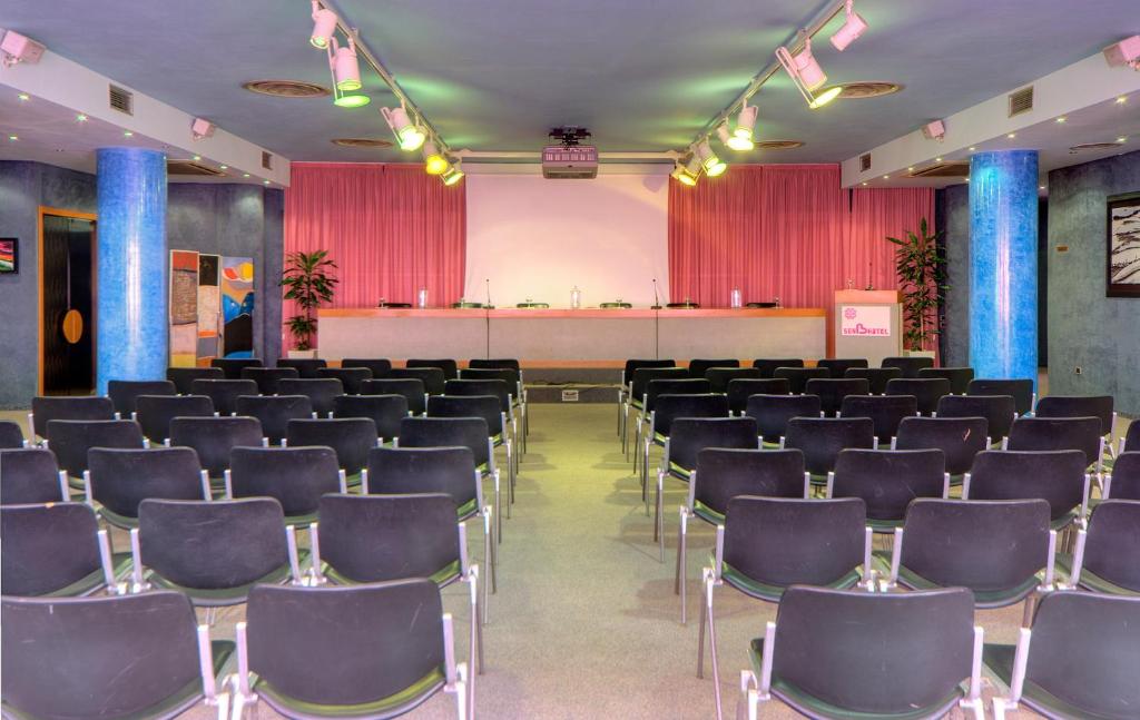 une salle de conférence avec des chaises et une scène dans l'établissement SenB Hotel, à Senigallia