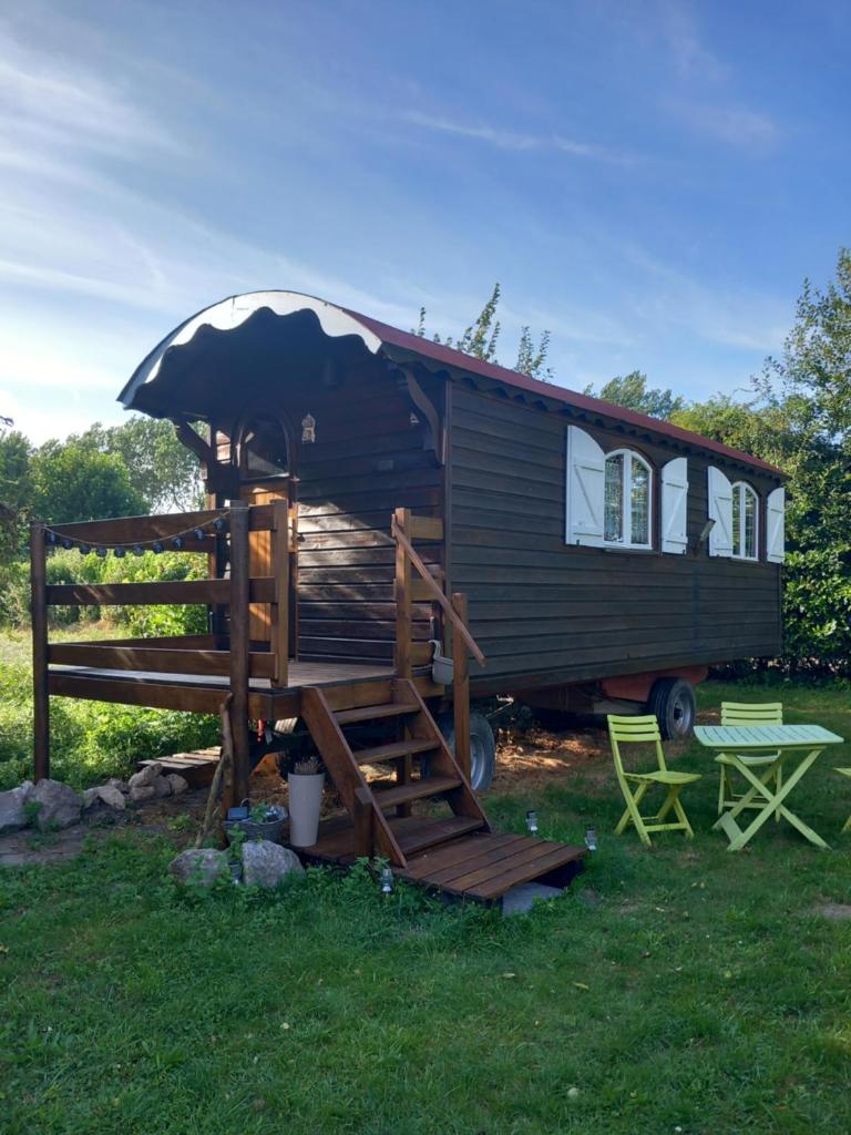 une petite maison avec une terrasse couverte et une balançoire dans l'établissement roulotte chez France, à Oye-Plage
