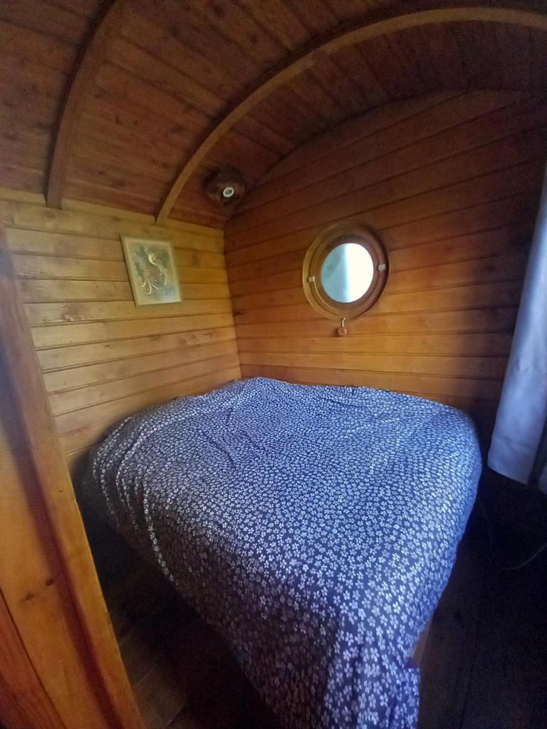 une petite chambre avec un lit dans un petit bateau dans l'établissement roulotte chez France, à Oye-Plage