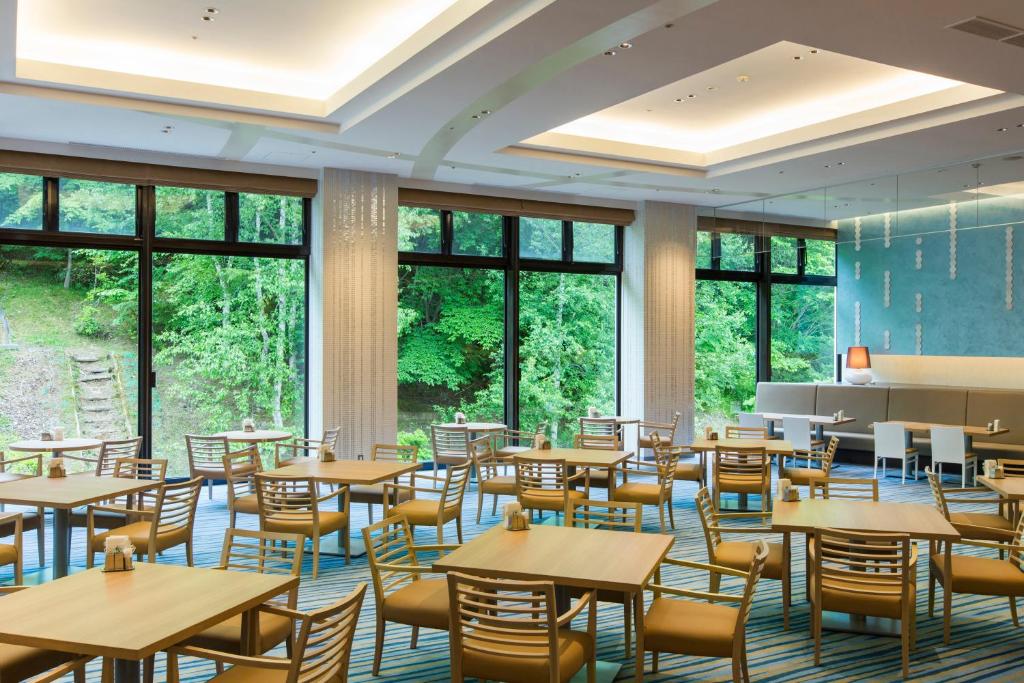 une salle à manger avec tables, chaises et fenêtres dans l'établissement Midorinokaze Resort Kitayuzawa, à Date