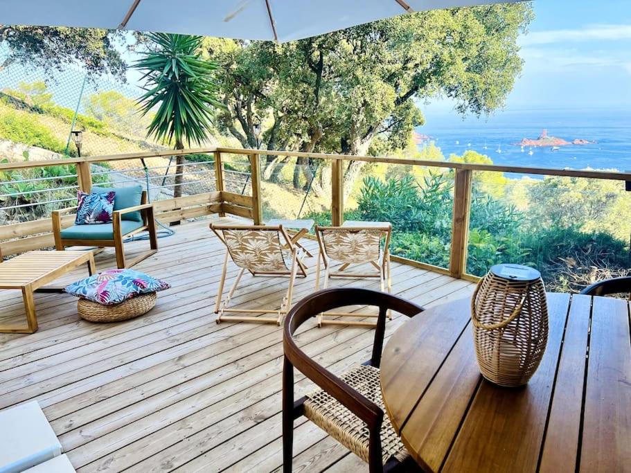 une terrasse en bois avec des chaises, une table et un parasol dans l'établissement La Cabane de Bob - Saint-Raphael, à Saint-Raphaël