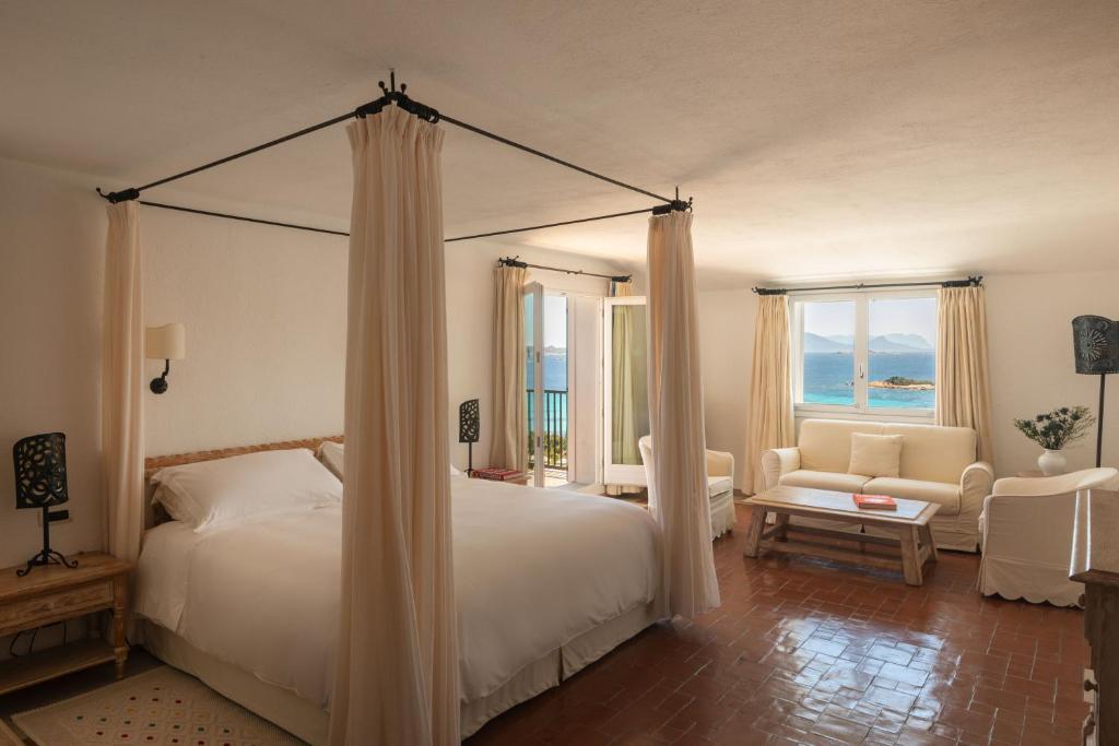 une chambre avec un lit à baldaquin et un salon dans l'établissement Romazzino, A Belmond Hotel, Costa Smeralda, à Porto Cervo