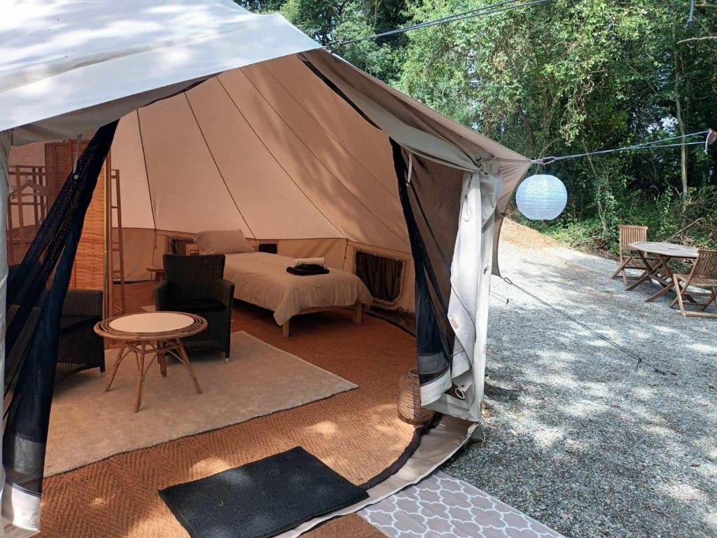 Cette grande tente comprend un lit et une table. dans l'établissement Glamping tent in de rust, met zwembad, badkamer en keuken, à Lacapelle-Pinet 14 autres photos