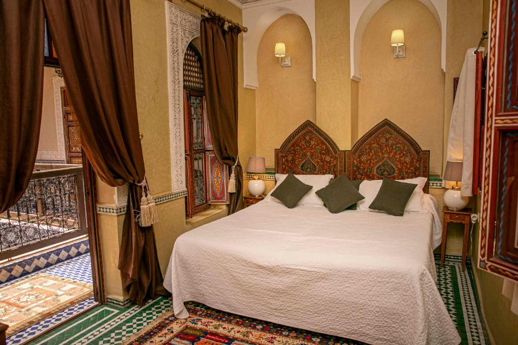 une chambre avec un lit avec des draps blancs et des oreillers dans l'établissement Riad Bab Chems, à Marrakech