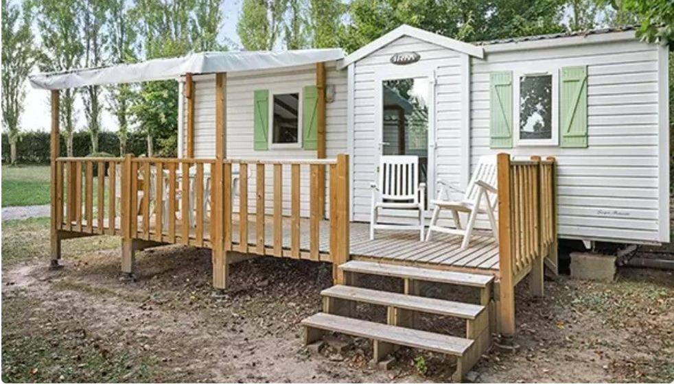 une maison avec une terrasse en bois et une chaise dans l'établissement Mobil-home camping la Dune Blanche, à Camiers