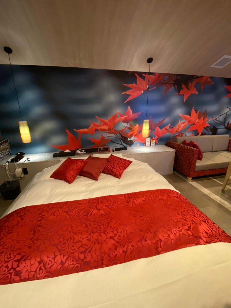 une chambre avec un grand lit avec des oreillers rouges dans l'établissement ホテル郷GO男塾ホテルグループAdult Only, à Yamatokoriyama