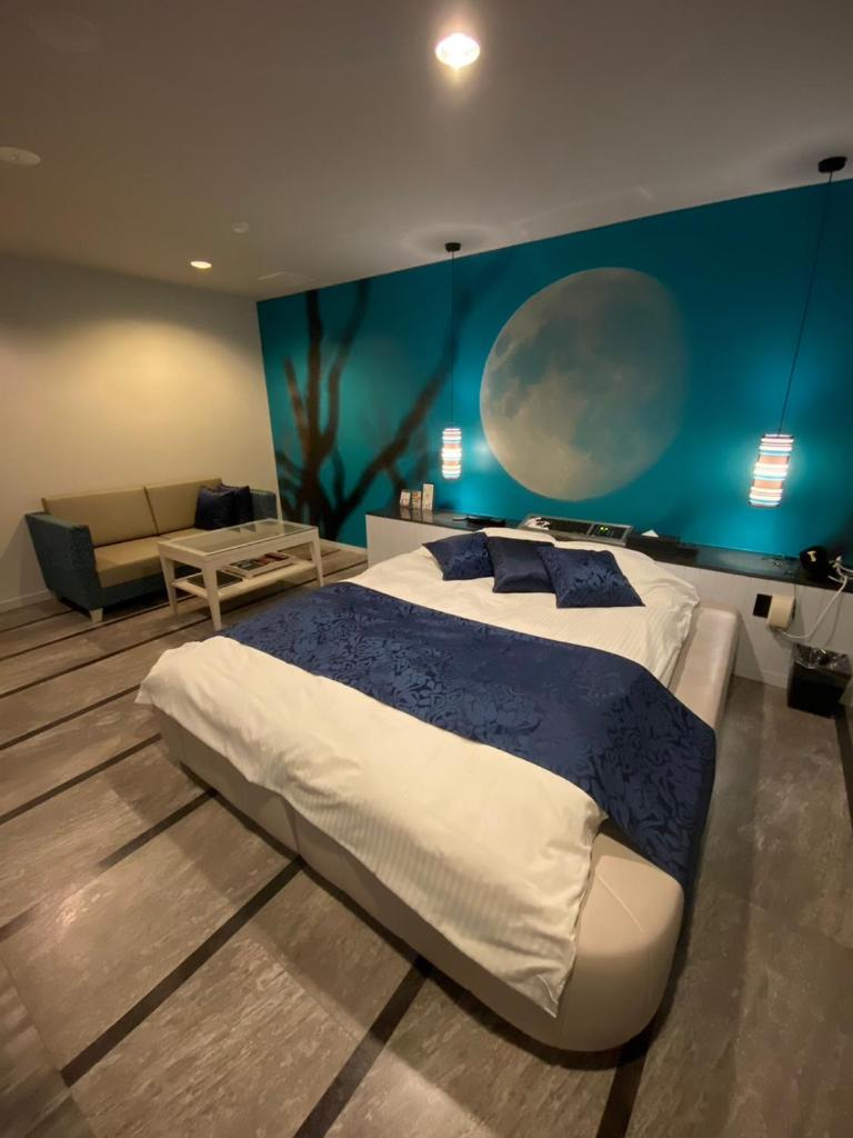 une chambre avec un grand lit et un mur bleu dans l'établissement ホテル郷GO男塾ホテルグループAdult Only, à Yamatokoriyama