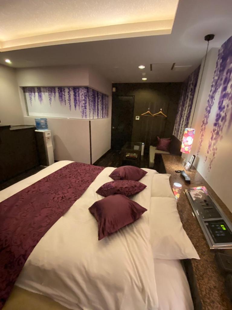 une chambre avec un grand lit avec des oreillers dessus dans l'établissement ホテル郷GO男塾ホテルグループAdult Only, à Yamatokoriyama