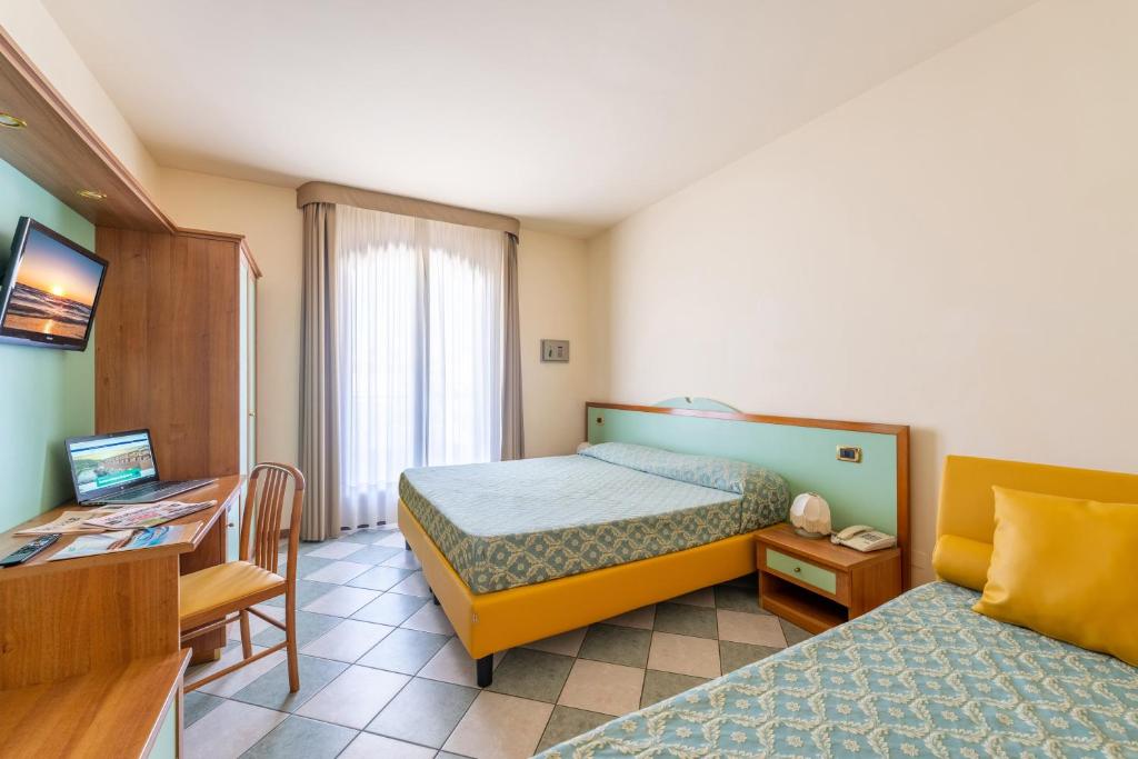 une chambre d'hôtel avec un lit, un bureau et un lit dans l'établissement Hotel Villa Elena, à Tortoreto Lido
