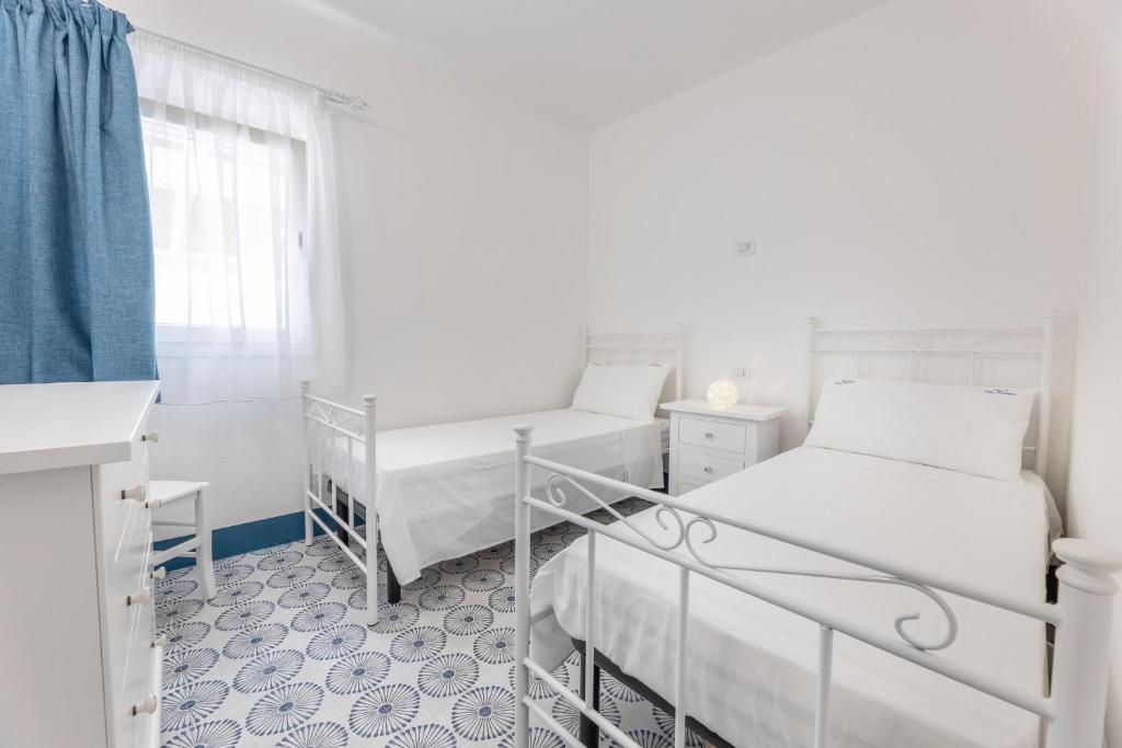 Cette chambre blanche dispose de deux lits et d'une fenêtre. dans l'établissement Villa Don Carmine, à Capilungo