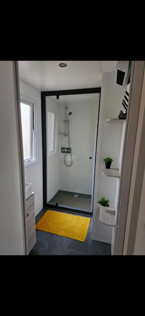 La salle de bains est pourvue d'une douche et d'un tapis jaune. dans l'établissement Superbe Mobil home proche de l'Océan, à La Roussellerie