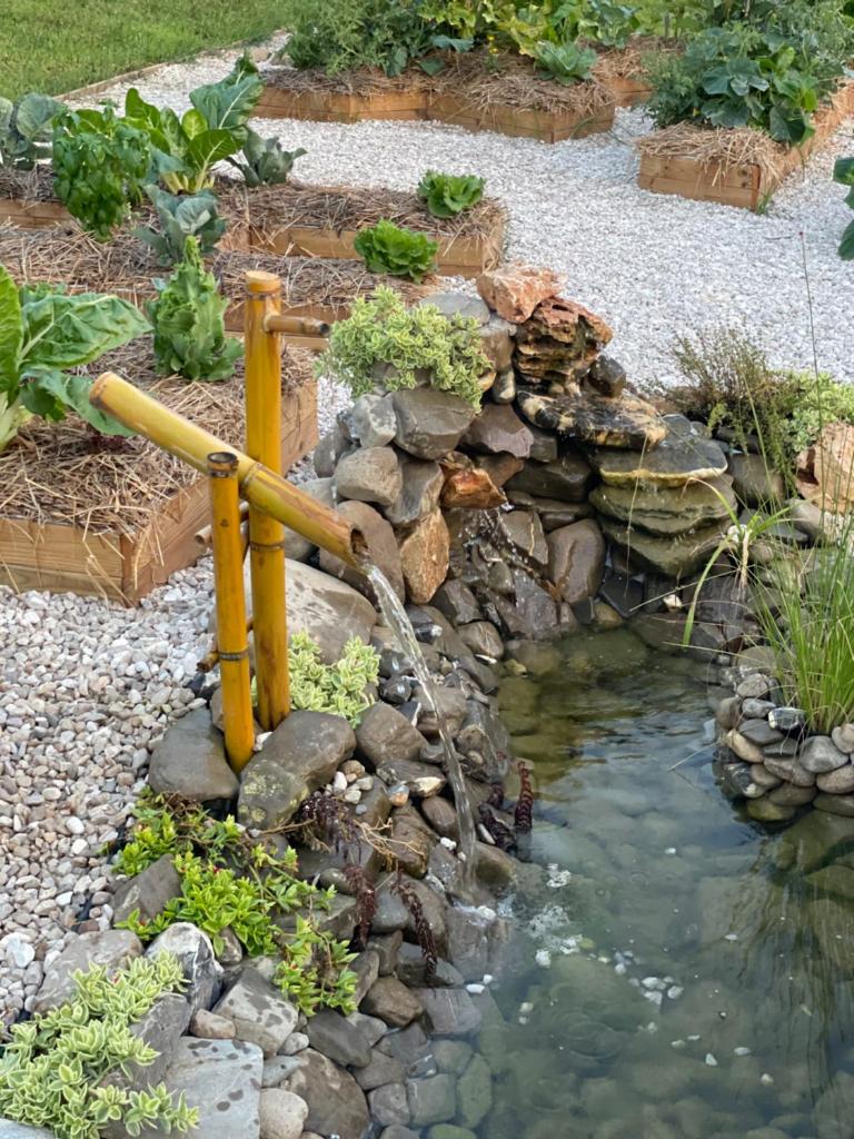 un étang avec une fontaine dans le jardin dans l'établissement Hotel Acciaroli, à Acciaroli