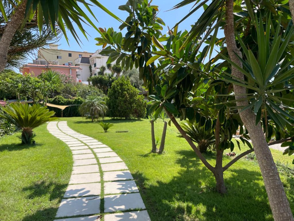 une allée dans un parc avec des palmiers dans l'établissement Hotel Acciaroli, à Acciaroli