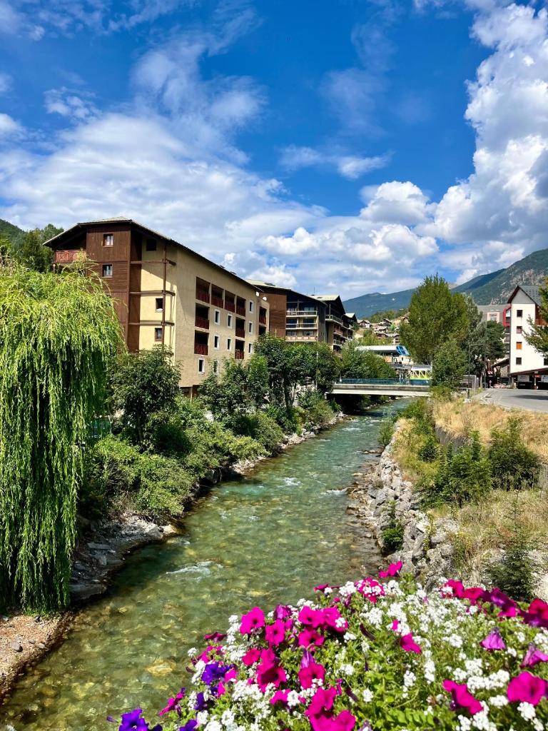 une rivière avec des fleurs devant un bâtiment dans l'établissement Charmant duplex pied de pistes Briançon, à Briançon