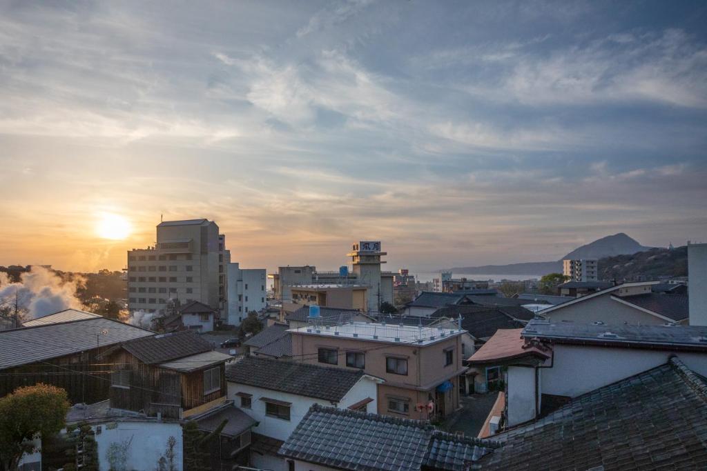 - une vue sur une ville avec des bâtiments et le coucher du soleil dans l'établissement 別府 鉄輪温泉 萬力屋別館 ManrikiyaBekkan Beppu Kannawa, à Beppu