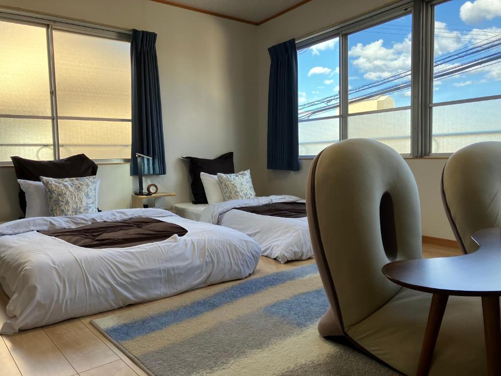 une chambre avec deux lits et une table et des chaises dans l'établissement 別府 鉄輪温泉 萬力屋別館 ManrikiyaBekkan Beppu Kannawa, à Beppu