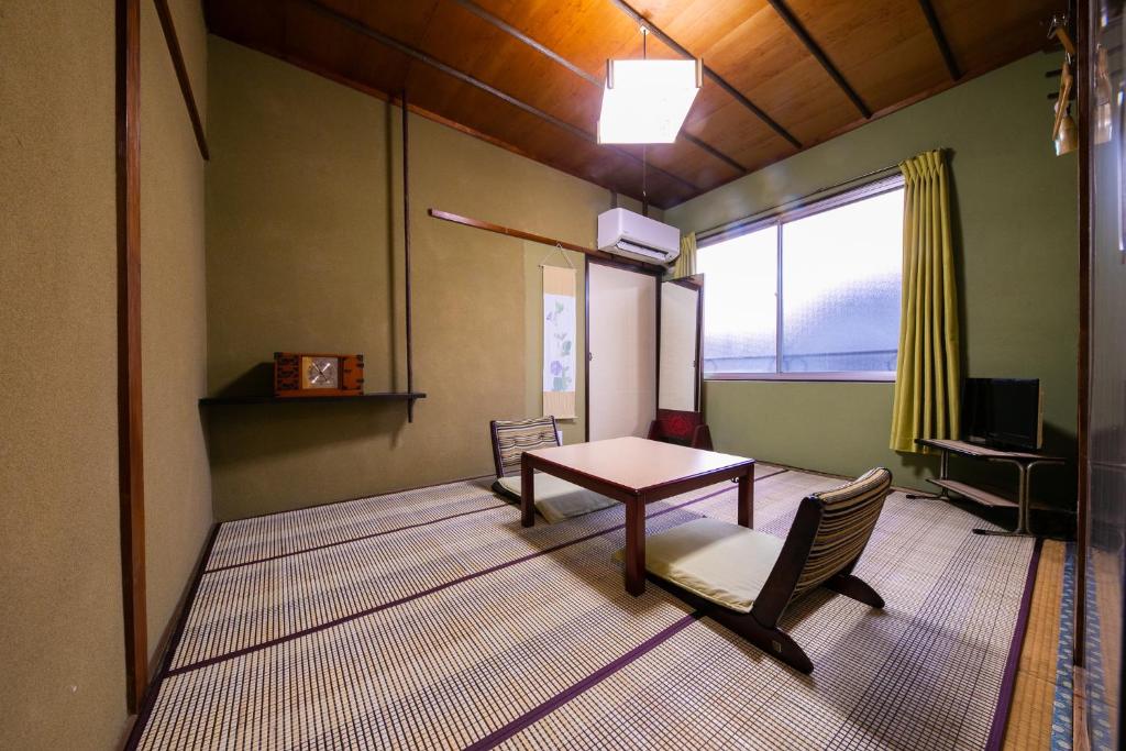 une pièce avec une table, des chaises et une fenêtre dans l'établissement 別府 鉄輪温泉 萬力屋別館 ManrikiyaBekkan Beppu Kannawa, à Beppu