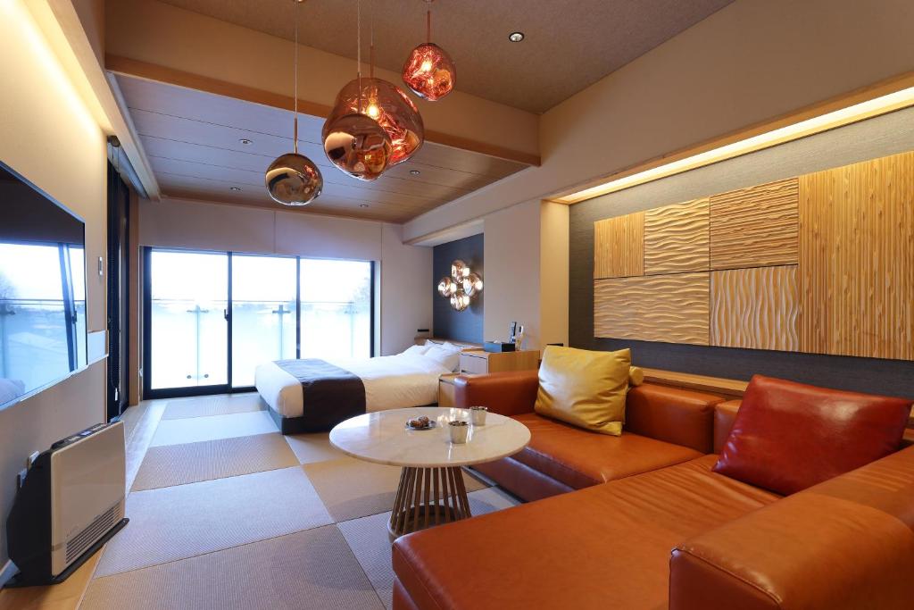 une chambre d'hôtel avec un canapé et un lit dans l'établissement Yorokobinoyado Takamatsu, à Kusatsu