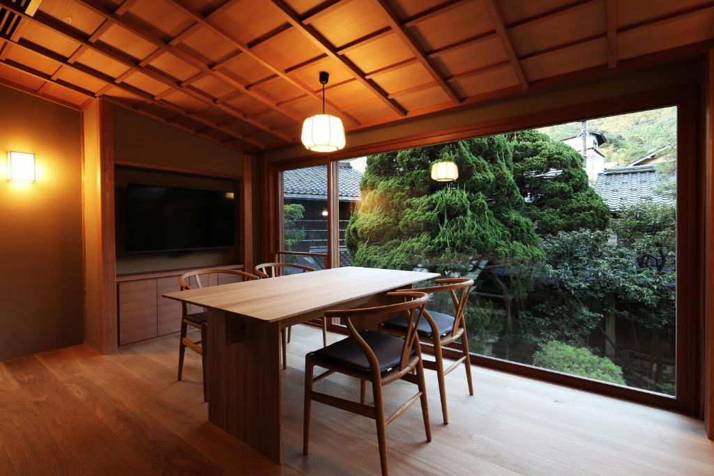 une salle à manger avec une table et des chaises et une grande fenêtre dans l'établissement Nishimuraya Honkan, à Toyooka