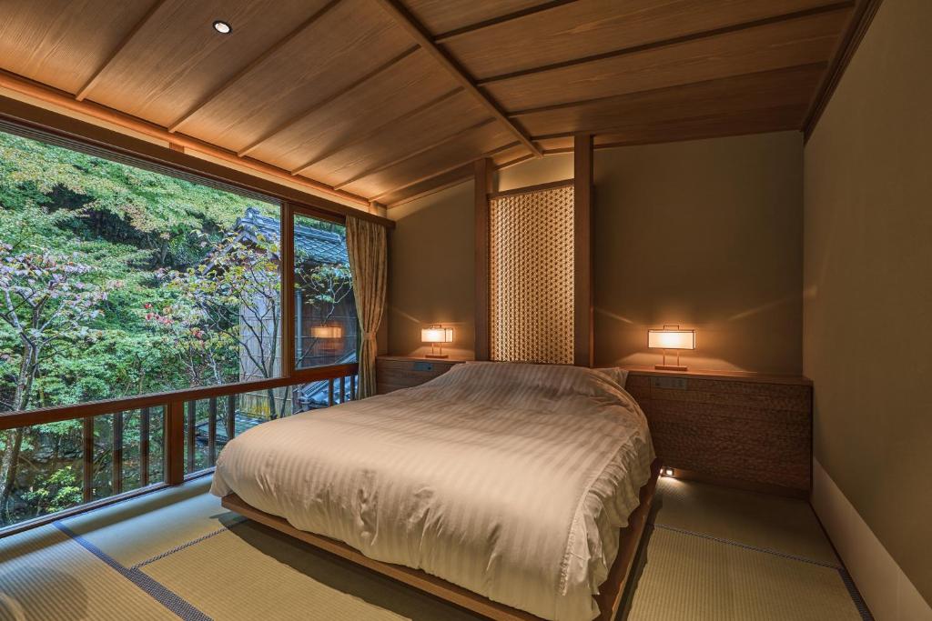 une chambre avec un lit et une grande fenêtre dans l'établissement Nishimuraya Honkan, à Toyooka 37 autres photos