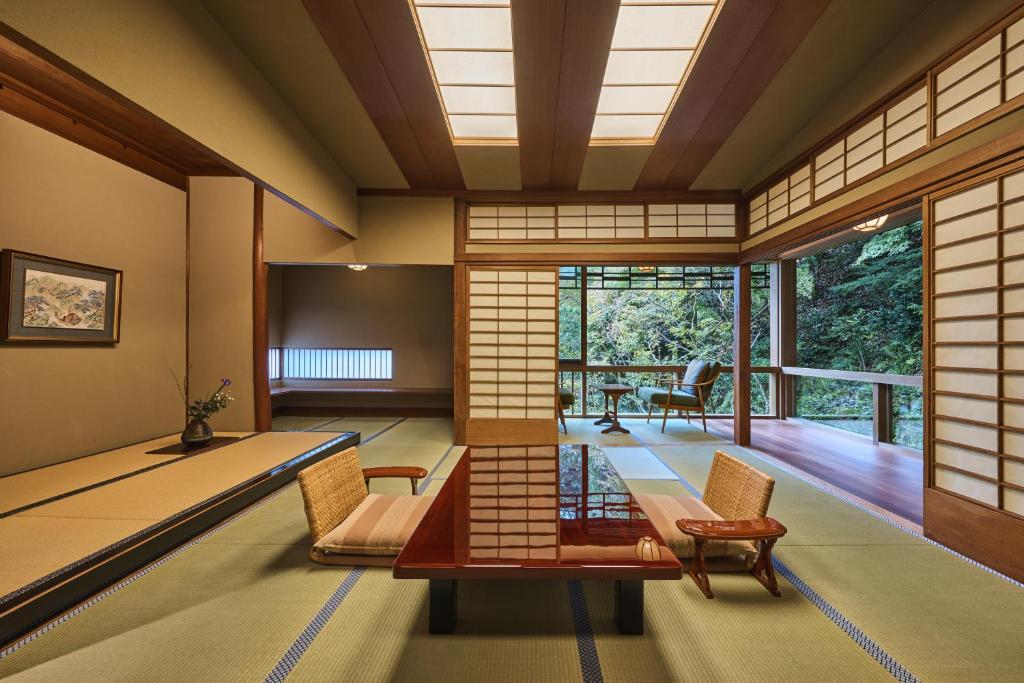 une chambre japonaise avec une table et des chaises dans l'établissement Nishimuraya Honkan, à Toyooka