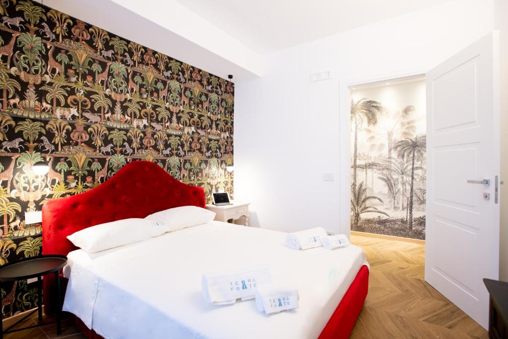 - une chambre avec un lit rouge et une fresque murale dans l'établissement TerraFORTE Luxury Sicilian Villa, à Marina di Ragusa