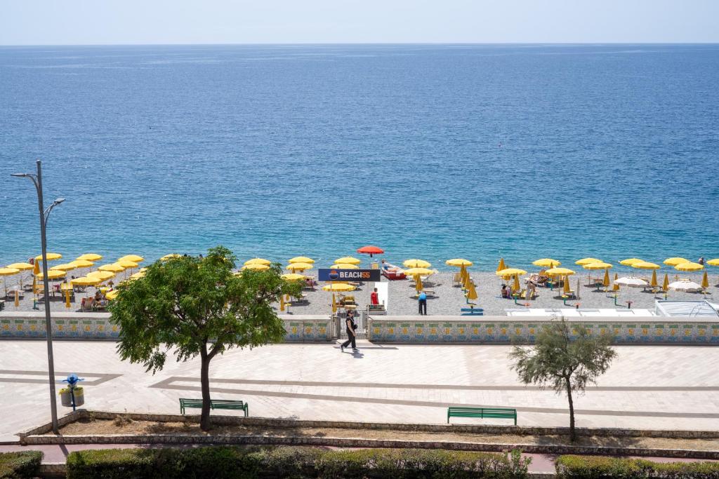 - un groupe de tables et de chaises avec parasols au bord de l'océan dans l'établissement Hotel Palace, à Catanzaro Lido