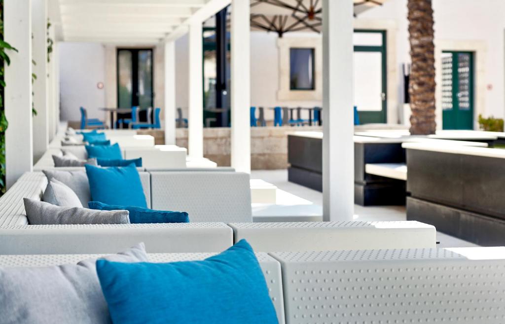 - une rangée de chaises longues blanches avec des oreillers bleus dans l'établissement Zafran Boutique Hotel, à Donnalucata