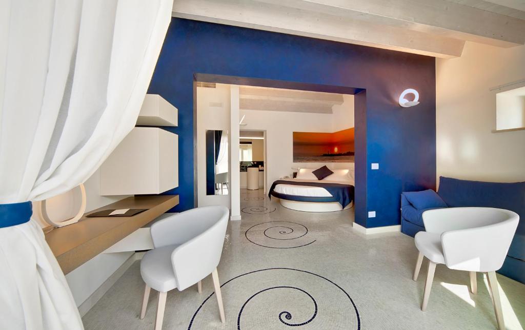 une chambre avec des murs bleus et un lit avec des chaises blanches dans l'établissement Zafran Boutique Hotel, à Donnalucata