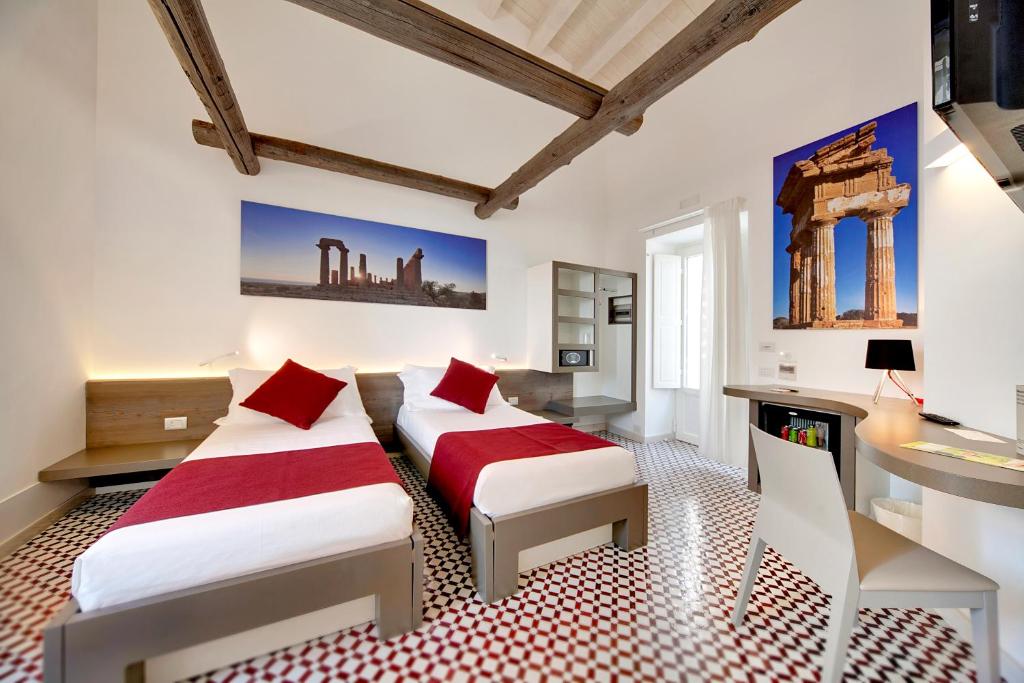 deux lits dans une chambre blanche avec des oreillers rouges dans l'établissement Zafran Boutique Hotel, à Donnalucata