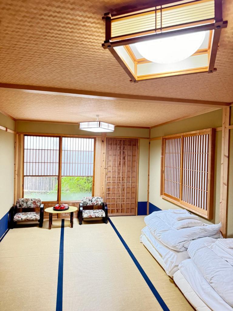 Cette grande chambre comprend deux lits et deux chaises. dans l'établissement Roman Kan, à Kyoto