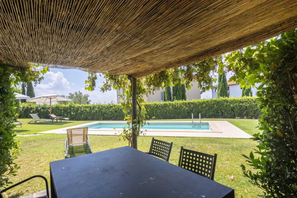 - une table et des chaises sous une pergola à côté de la piscine dans l'établissement Villa il Fienile by VacaVilla, à Lamporecchio