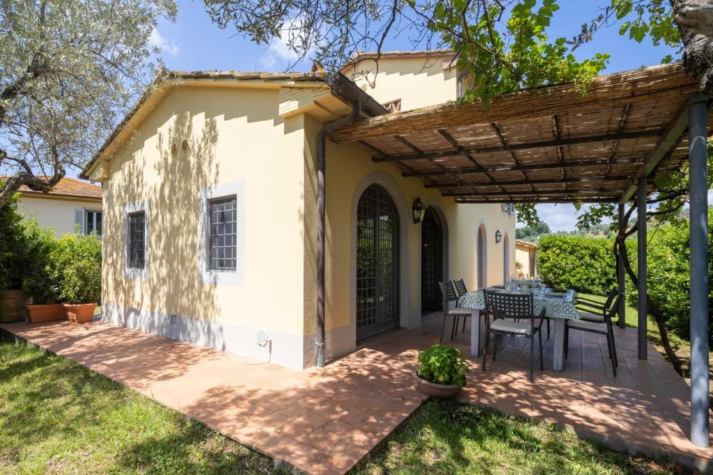 un patio avec une table et des chaises sous une pergola en bois dans l'établissement Villa il Fienile by VacaVilla, à Lamporecchio 19 autres photos