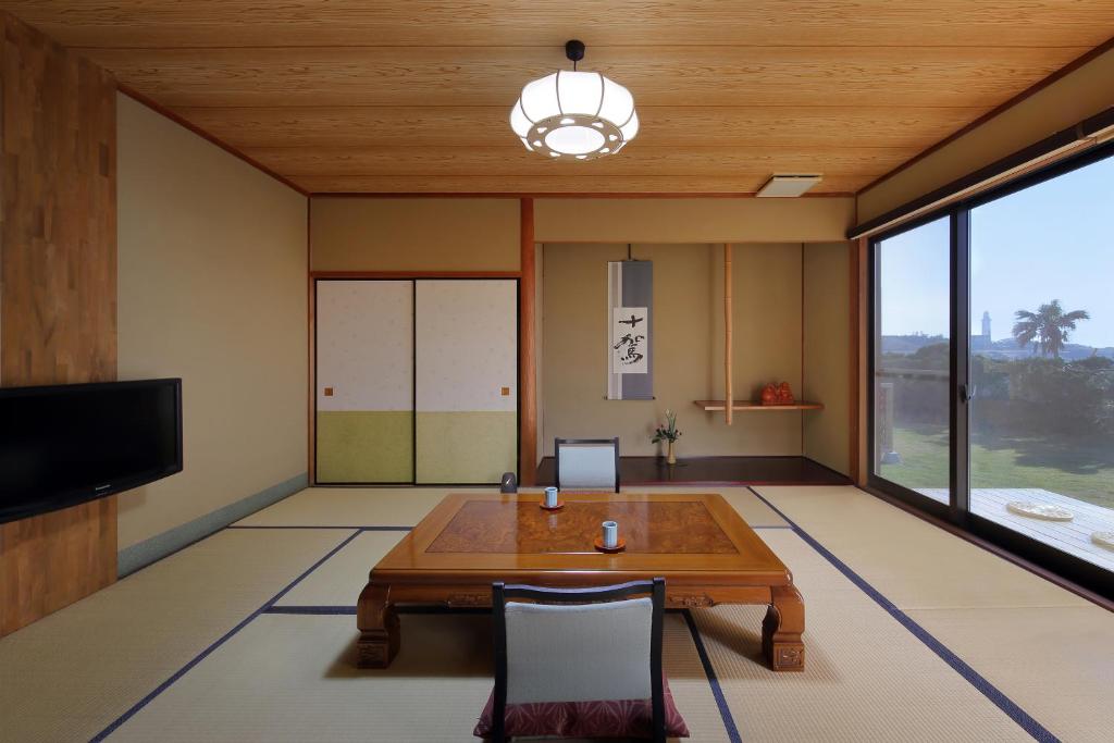 un salon avec une table et une télévision dans l'établissement 季粋の宿 紋屋, à Hongō