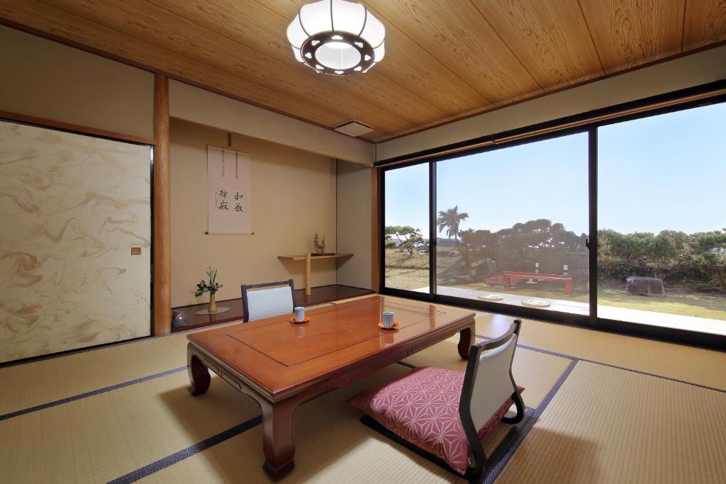 un bureau avec une table et des chaises en bois et de grandes fenêtres dans l'établissement 季粋の宿 紋屋, à Hongō