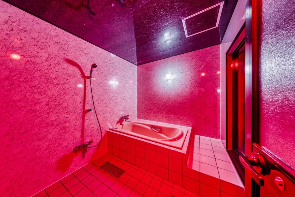 La salle de bains rouge est pourvue d'un lavabo et d'une douche. dans l'établissement HOTEL ABnormal (Adult Only), à Izumiotsu