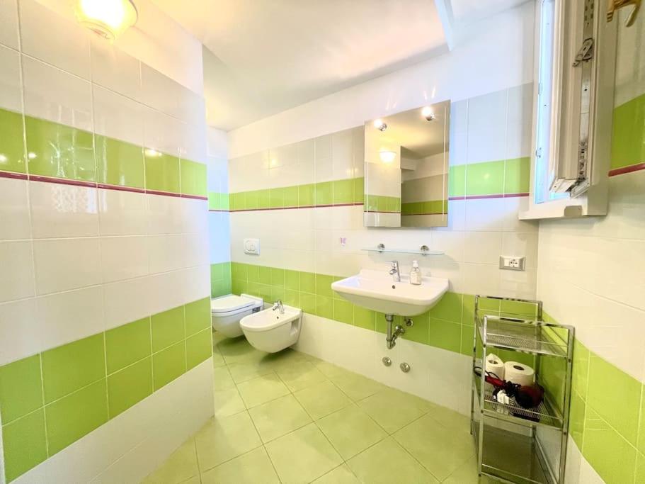 - une salle de bains verte et blanche avec lavabo et toilettes dans l'établissement Villa Licia, à Gardone Riviera